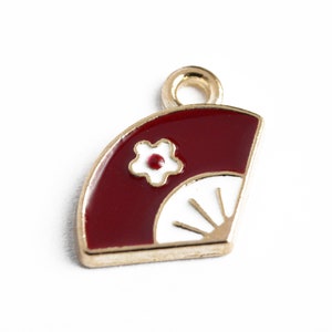 May include: Gold charm with a red and white enamel fan design. The fan has a white flower with a red center.