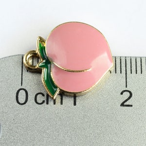 May include: Gold-tone peach charm with a green leaf, measuring approximately 1 cm in length.