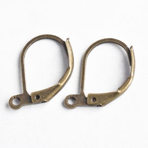 May include: Two antique gold-toned earring hooks. The hooks are made of metal and have a simple, classic design.