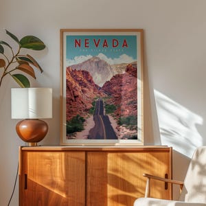 a framed poster of a scenic road winding through a mountainous landscape, with the text "NEVADA THE SILVER STATE" prominently displayed.