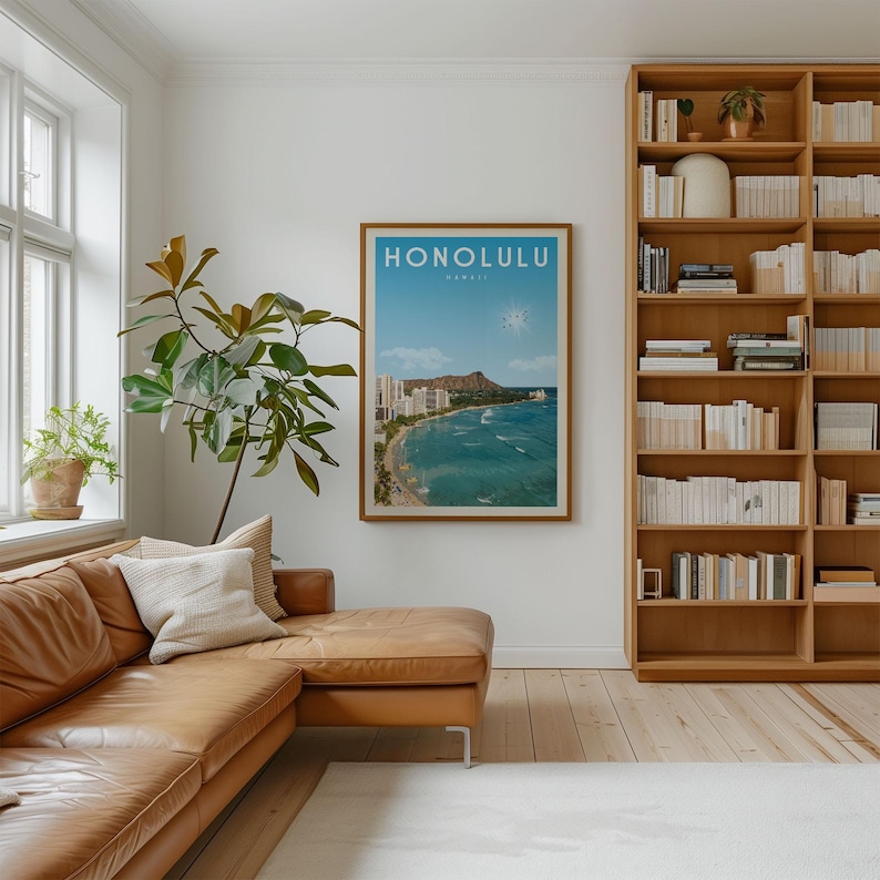 a cozy living room with a large window, a comfortable leather couch, a bookshelf filled with books, and a framed poster of Hawaii on the wall.