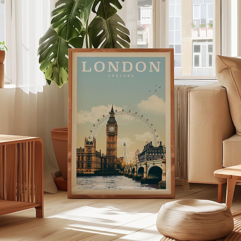 A framed poster of London, England, featuring the iconic Big Ben and the London Eye, is displayed in a living room setting with a potted plant and a window in the background.