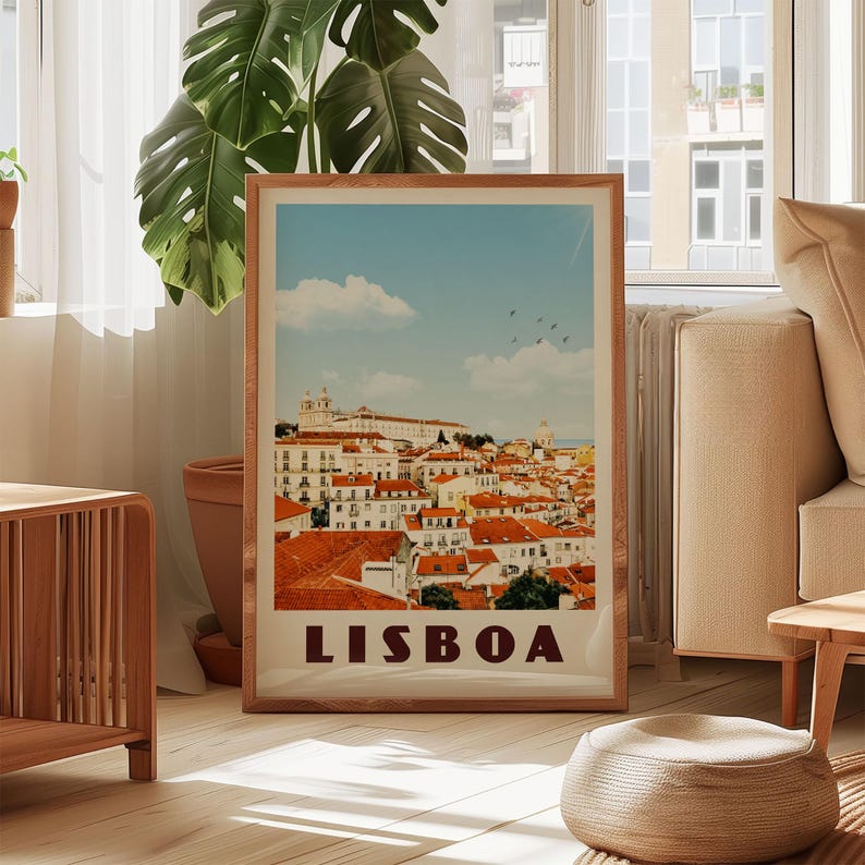 A framed poster of Lisbon, Portugal, displayed in a living room with a large window and a potted plant in the background.