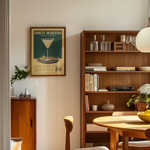 a cozy living room with a wooden bookshelf, a framed poster of a dirty martini, and a wooden cabinet. The room has a warm and inviting atmosphere, with a dining table and chairs in the foreground.