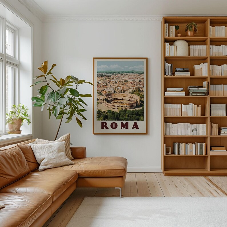 a cozy living room with a large window, a comfortable leather couch, a bookshelf filled with books, and a framed poster of the Colosseum hanging on the wall.