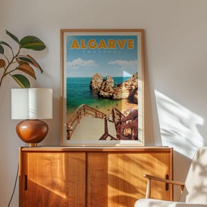 a framed poster of a beach scene with a wooden staircase leading to a cliff, set against a blue sky with clouds.