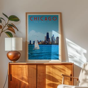 a framed poster of Chicago's skyline, with a sailboat in the foreground, placed on a wooden cabinet.