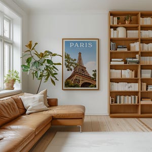 a cozy living room with a large framed poster of the Eiffel Tower hanging on the wall, a comfortable leather couch, and a bookshelf filled with books.