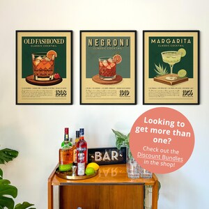 a wall with three framed posters of classic cocktails, each with a different cocktail image and description. Below the posters, there is a wooden bar with various bottles and glasses, and a sign that reads "BAR".