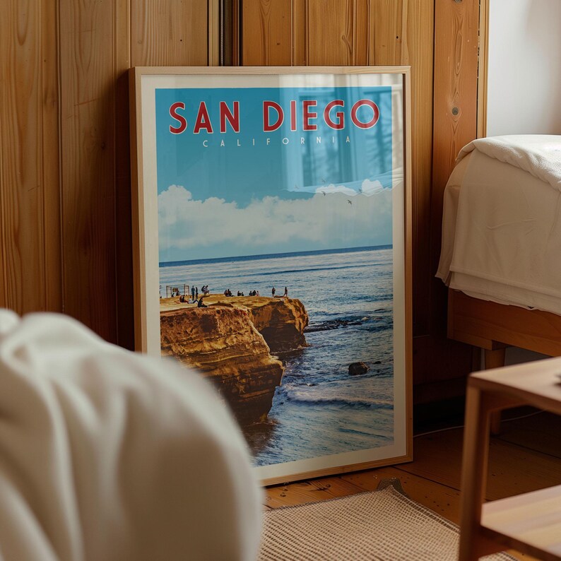 A framed poster of a scenic coastal landscape with cliffs and people enjoying the view, displayed in a room with wooden walls.