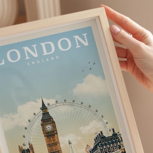 A person's hand is holding a framed picture of the London skyline, including the iconic Big Ben and the London Eye ferris wheel.