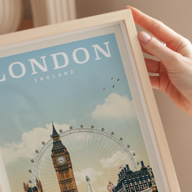 A person's hand is holding a framed picture of the London skyline, including the iconic Big Ben and the London Eye ferris wheel.