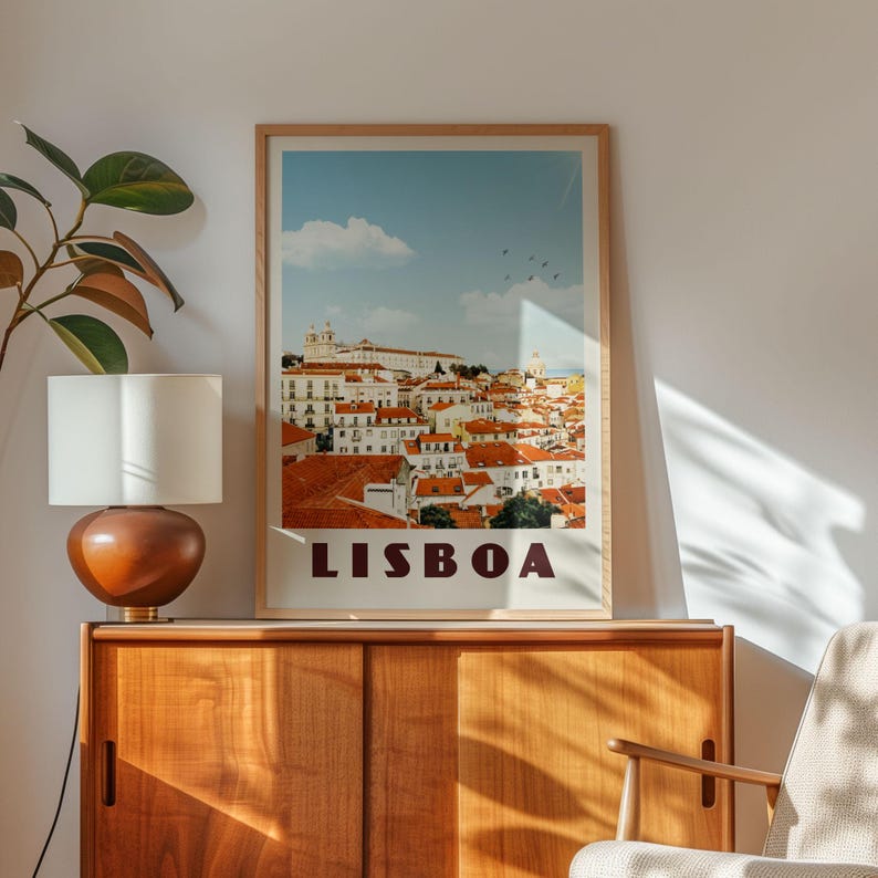 a framed poster of Lisbon, Portugal, hanging on a wall above a wooden cabinet.