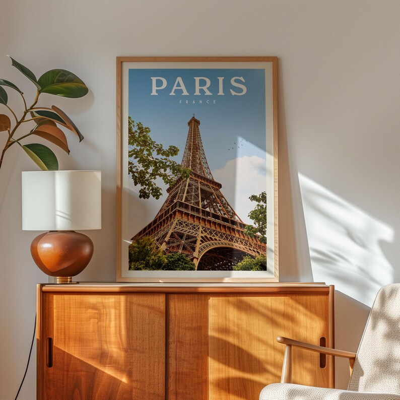 a framed picture of the Eiffel Tower in Paris, France, hanging on a wall above a wooden cabinet.