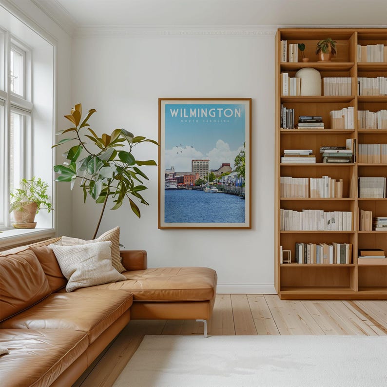a cozy living room with a large bookshelf filled with books, a comfortable leather couch, and a framed poster of a cityscape hanging on the wall.