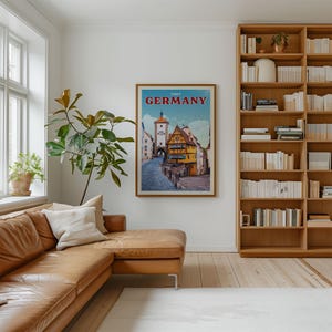 a cozy living room with a large bookshelf filled with books, a comfortable leather couch, and a framed poster of a German town hanging on the wall.