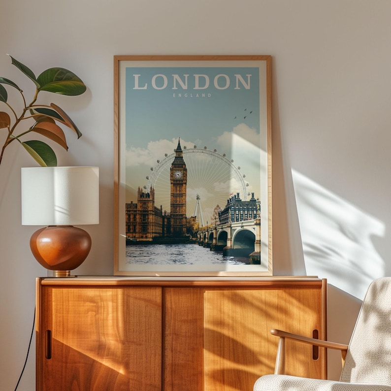 a framed poster of London, England, with the iconic Big Ben and the London Eye visible, displayed on a wooden cabinet or shelf.