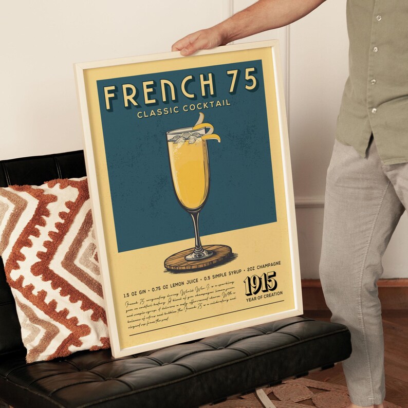A person is holding up a framed poster advertising a French 75 cocktail.