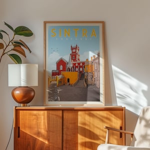 a framed poster of Sintra, a city in Portugal, hanging on a wall above a wooden cabinet.