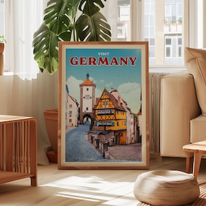 a framed poster of a German town, with a clock tower and colorful buildings, displayed in a living room setting.