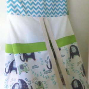 May include: A hanging storage bag with a blue and white chevron pattern at the top. The main body is white with green trim and a pattern of elephants in blue and green. The word "swish" is printed on the bag.