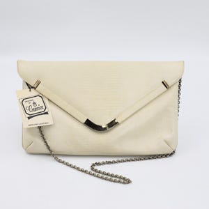 May include: Cream-coloured envelope clutch bag with a textured surface and silver-tone hardware. Features a chain strap and a tag that reads "Designed by Caprice, Genuine Leather."