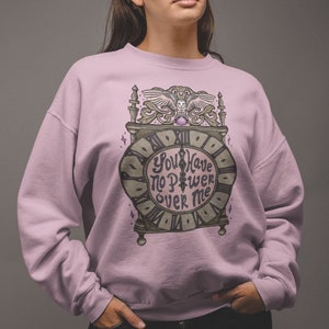 May include: A light pink sweatshirt with a graphic of an ornate clock with the text "You Have No Power Over Me".