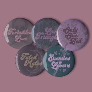 May include: Five round buttons with different romantic themes. The buttons are purple, teal, and gray with gold lettering. The text on the buttons reads "Forbidden Love", "Love Triangle", "Only One Bed", "Fated Mates", and "Enemies to Lovers".