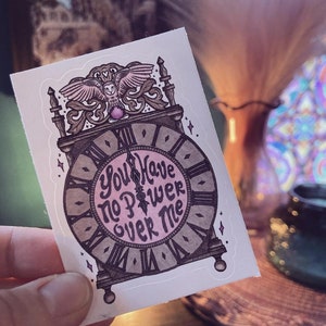 May include: A sticker featuring a vintage clock with an owl perched on top. The clock face reads "You Have No Power Over Me".