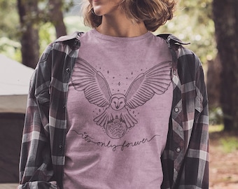 May include: A woman wearing a pink t-shirt with a black and white owl graphic and the text "forever only forever". She is standing in a forest with a dog and camping gear.