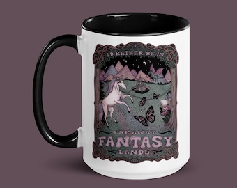 May include: White ceramic mug with a black rim and handle. The mug features a whimsical illustration of a unicorn, a castle, and a dragon in a fantasy landscape. The text reads "I'd rather be in faraway fantasy lands".