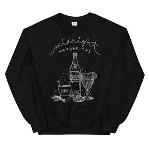 May include: Black sweatshirt with a white graphic design of a bottle of tequila, a mortar and pestle, a lime, and a glass with a lime wedge. The text "midnight margaritas" is written in a cursive font above the graphic.
