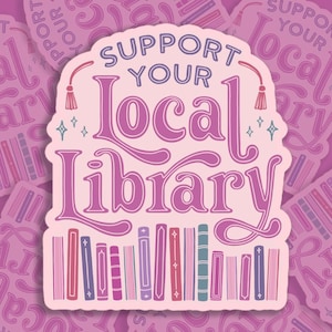 May include: Pink sticker with the text "Support Your Local Library" in a decorative font. The sticker features a row of colourful books at the bottom and a pink tassel on each side.