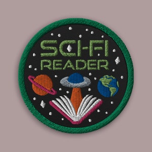 May include: A green, round embroidered patch with the text "Sci-Fi Reader" in green letters. The patch features a white book with pink pages, a spaceship, a planet, and a star field.