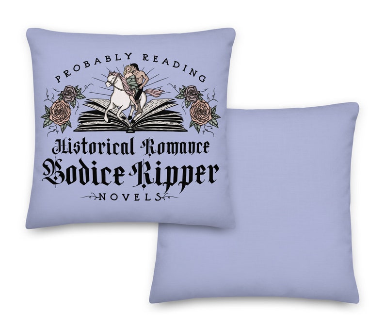 May include: A light blue throw pillow with a white design. The design features a couple riding a horse on top of an open book. The text reads "Probably Reading Historical Romance Bodice Ripper Novels".