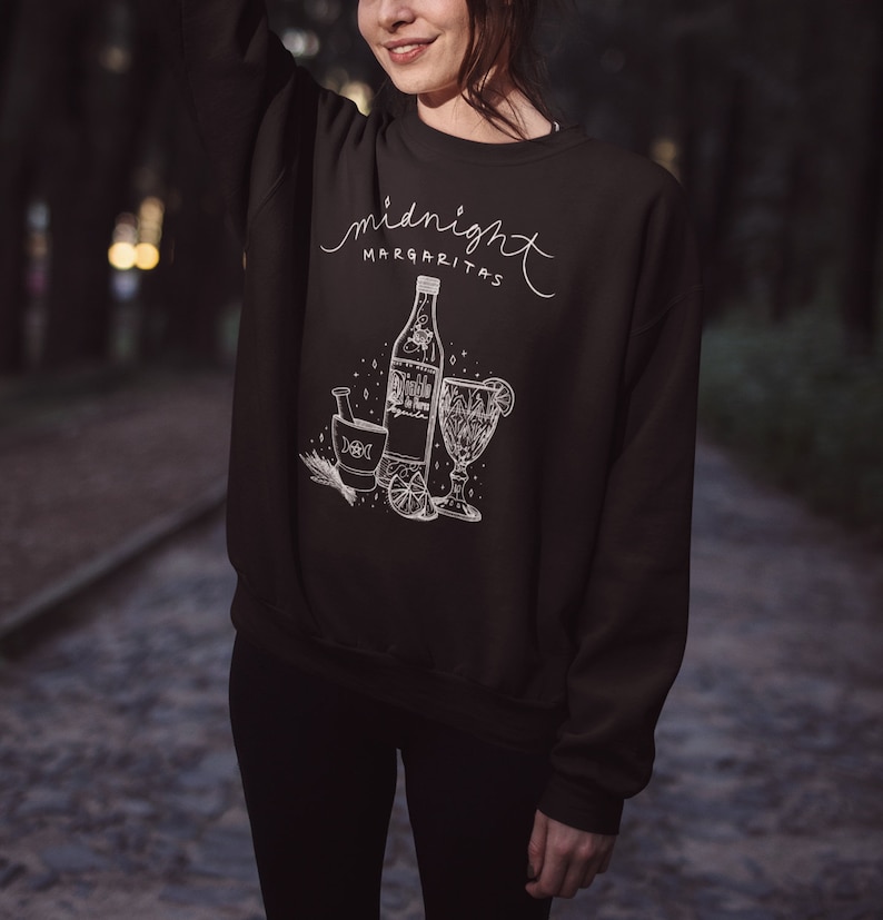 May include: Black sweatshirt with a white graphic design of a bottle, a glass, and a mortar and pestle. The text "midnight margaritas" is written above the graphic.