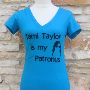 May include: A turquoise blue t-shirt with a black graphic that says "Tami Taylor is my Patronus".
