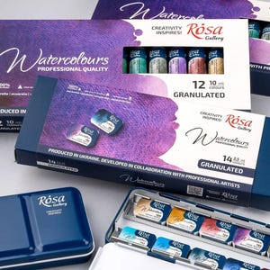 May include: A set of Rosa Gallery professional quality granulated watercolor paints in rectangular boxes. The packaging features purple and white branding with the text Watercolours. One open metal tin displays individual paint pans in various colors.