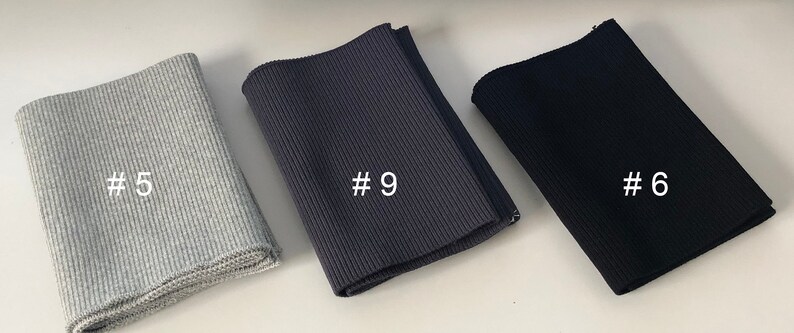 May include: Three different colors of ribbed knit fabric, labeled #5, #9, and #6. The fabric is folded and appears to be a type of elastic knit.