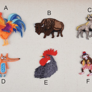 May include: Six embroidered iron-on patches featuring a rooster, a buffalo, a ram, a fox, a rooster, and a monkey. The patches are colorful and detailed.