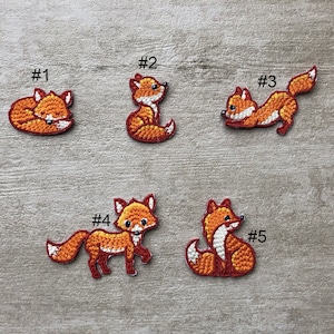 Op de afbeelding: Vijf geborduurde strijkpatches met oranje vossen in verschillende poses. De patches zijn genummerd van 1 tot en met 5.