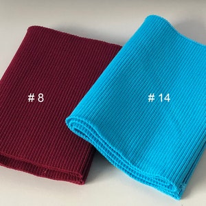 May include: Two pieces of ribbed knit fabric, one burgundy and one turquoise, folded and labeled with the numbers #8 and #14.