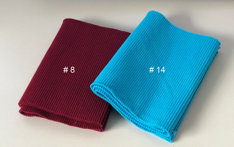 May include: Two pieces of ribbed knit fabric, one burgundy and one turquoise, folded and labeled with the numbers #8 and #14.
