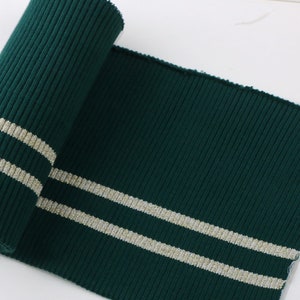 May include: Green ribbed knit fabric with two silver stripes. This fabric is perfect for adding a touch of style to your sewing projects.