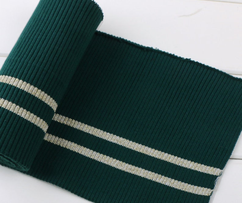 May include: Green ribbed knit fabric with two silver stripes. This fabric is perfect for adding a touch of style to your sewing projects.