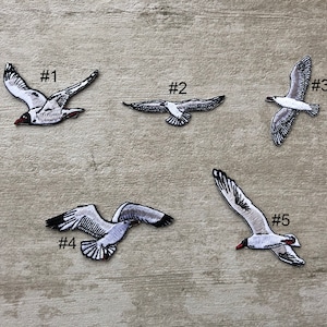 May include: Five white seagull iron-on patches with black eyes and red beaks. The patches are numbered 1 through 5.