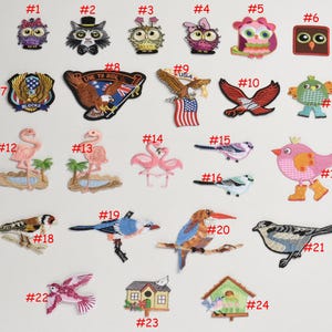 May include: A set of 24 iron-on patches featuring various designs, including animals, flags, and phrases. The patches are numbered 1 through 24 and are arranged in rows on a white background.
