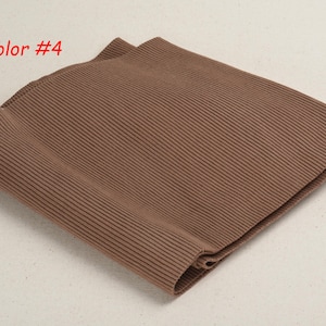 K&ouml;nnte beinhalten: Nahaufnahme eines braunen Rippstoffs. Der Stoff ist in der Mitte gefaltet und hat eine weiche, strukturierte Oberfl&auml;che. Der Text "Color #4" ist in der oberen linken Ecke des Bildes sichtbar.