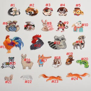 Könnte beinhalten: Set mit 24 Bügelbildern mit verschiedenen Tiermotiven, darunter ein Hahn, ein Lama, ein Fuchs, ein Waschbär, ein Eichhörnchen, ein Chamäleon und ein Schmetterling. Die Bügelbilder sind von 1 bis 24 nummeriert.