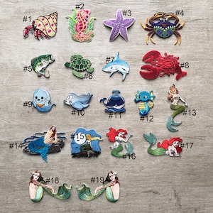 以下が含まれることがあります： 様々な海の生き物を描いた刺繍パッチのコレクション。ヤドカリ、タツノオトシゴ、ヒトデ、カニ、魚、カメ、サメ、ロブスター、幽霊、アザラシ、クジラ、タツノオトシゴ、人魚など。各パッチはユニークな配色と複雑なディテールを持っています。